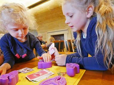Zwei Mädchen sitzen an einem Spieltisch und 