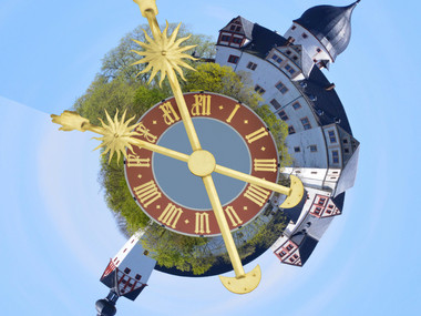 Das Bild zeigt die Rochsburg in runder Form, als Uhr dargestellt, in der Mitte befinden sich zwei goldene Uhrzeiger.