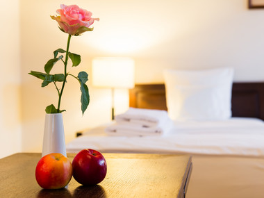 Eine Rose steht auf dem Schrank vor dem Hotel Bett im Schlosshotel Purschenstein